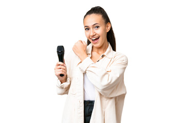 Young singer woman picking up a microphone over isolated chroma key background celebrating a victory