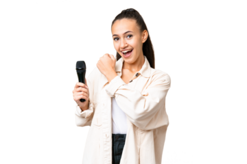 Young singer woman picking up a microphone over isolated chroma key background celebrating a victory