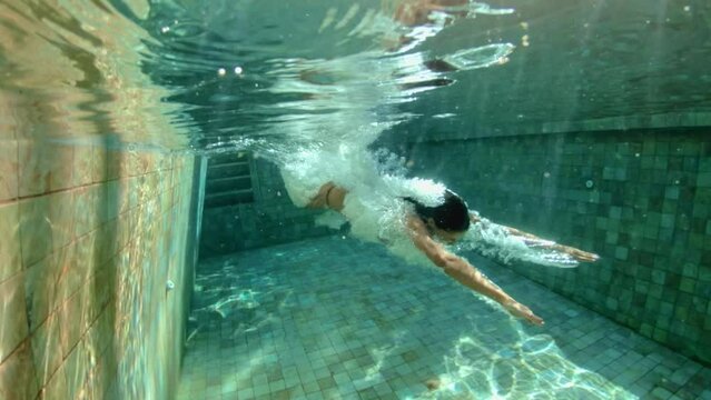 Active young woman jump and dive underwater in a blue swimming pool. Travel lifestyle, water sport, snorkeling adventure. Summer sea beach vacation . Young female swimmer shooting herself while