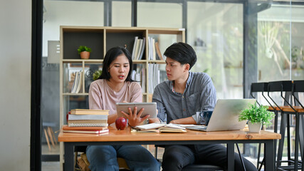 Two Asian friends are discussing work and working on their co-project at a cafe together