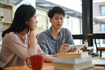 A smart and focused Asian male college student tutoring and helping his friend with math