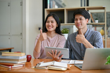 Two Asian college students are showing their thumbs up while studying