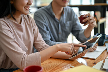 Close-up image of two happy young Asian college students are looking at a tablet screen together