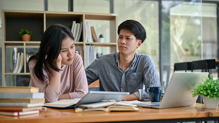 A caring Asian man is comforting to his upset and stressed-out girl friend while studying together.