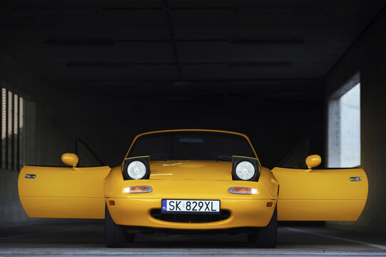 Auto mazda  model mx-5   1995 r. miata w kolorze sun burst yellow gen N po liftingu zaparkowana na parkingu widok z zewnątrz.