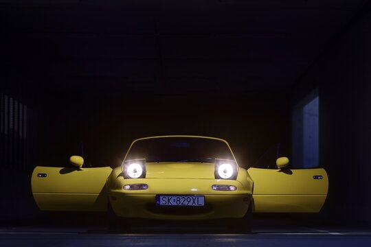 Auto mazda  model mx-5   1995 r. miata w kolorze sun burst yellow gen N po liftingu zaparkowana na parkingu widok z zewnątrz.