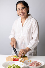 Asian elderly woman preparing Thai food ingredients in the kitchen