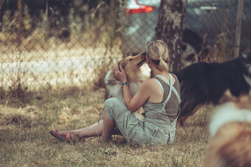 Frau sitzend auf Gras mit Collie sable schmusen, inniges Verhältnis Mensch Tier