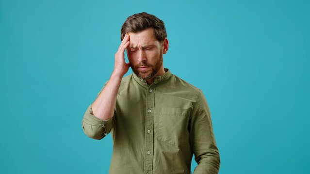 Young bearded man massages temples suffering from headache
