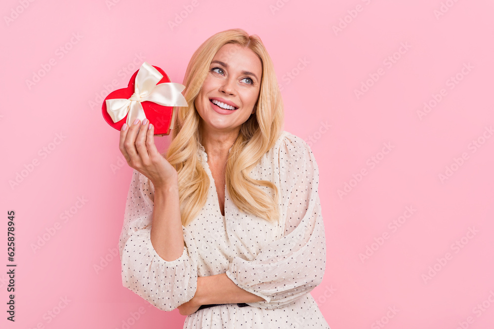 Wall mural Photo portrait of attractive blonde woman red heart box look empty space dressed stylish white clothes isolated on pink color background