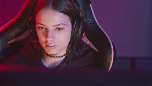 Waist up slowmo of concentrated Caucasian gamer girl winning in night cybersport tournament, rejoicing her victory at dark computer club
