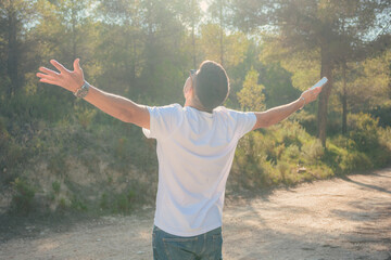 Latin man opening his arms in a forest. Expression of freedom