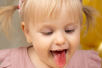 Little girl with red tongue from dye after eating cake.