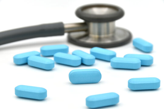 Stethoscope and blue caplet medicine on white background.