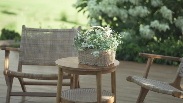 flower bouquet in wicker basket on wood table in garden