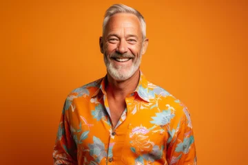 Gardinen Portrait of a happy senior man in a colorful shirt over orange background. © igolaizola