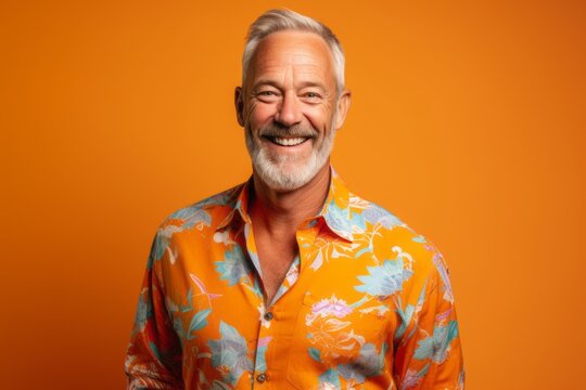 Portrait Of A Happy Senior Man In A Colorful Shirt Over Orange Background.