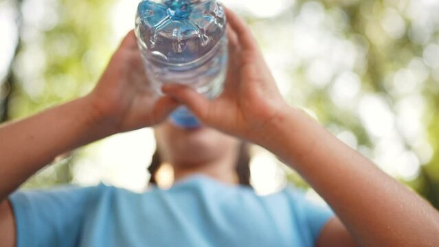 child drinking water from a plastic bottle lifestyle. water shortage problem on earth concept. water shortage problem on earth concept. kid drinks water in nature from a bottle glare of the sun summer