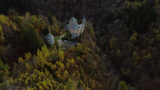 Majestic medieval castle hidden in deep forest valley, aerial view