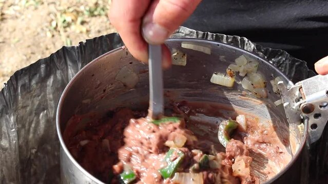 stirring up beans in a pot outside