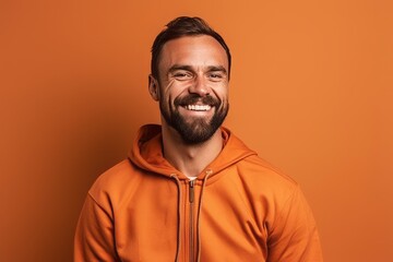 smiling man in orange hoodie looking at camera isolated on orange - obrazy, fototapety, plakaty