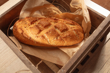 Barra de pan tostado sobre caja de madera, vista cenital. Loaf of toasted bread on a wooden box, overhead view.