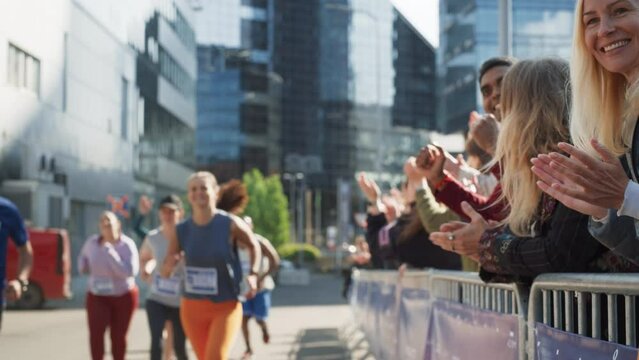 Marathon Audience Supporting and Cheering Their Loved Ones Participating in the Race: Athletic Male Marathon Runner Giving a High Five to Female Family Member in the Audience While Running