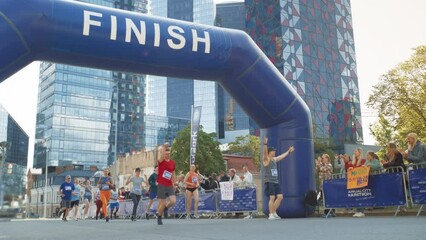 Slow Motion Portrait of a Smiling Group of People Participating in a City Marathon. Wide Shot of Diverse Race Runners Reaching the Finish Line, Celebrating Their Victory and Achieving their Goal