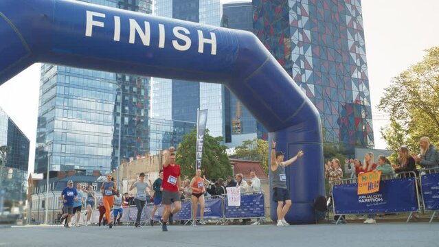 Slow Motion Portrait of a Smiling Group of People Participating in a City Marathon. Wide Shot of Diverse Race Runners Reaching the Finish Line, Celebrating Their Victory and Achieving their Goal