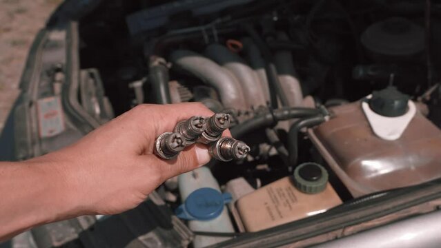 Spark plug. Master's hand shows to camera four candles used with soot and plaque, because of which engine was not produced or badly worked. Gasoline candles. Troubleshooting and troubleshooting.