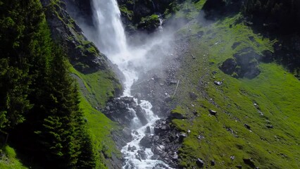 Drone tilt up pan reveals strong flowing river and cascading waterfall over black basalt