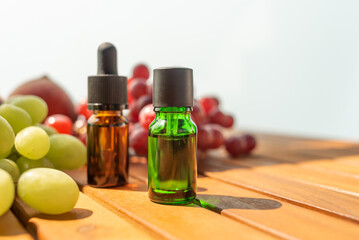 two bottles of essential oils. natural cosmetics for skin care. A bottle and fresh peaches and grapes on a wooden table. Taking care of health and beauty.