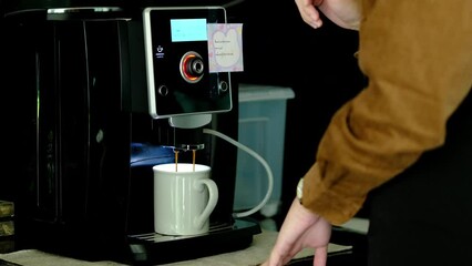 Unrecognizable woman preparing fresh aromatic coffee, using a coffee machine maker in cozy office kitchen