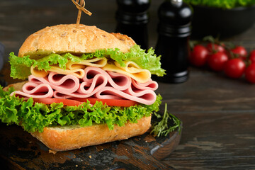 Sandwich. Tasty sandwich with ham or bacon, cheese, tomatoes, lettuce and grain bread on dark backgrounds. Delicious club sandwich or school lunch, breakfast or snack.