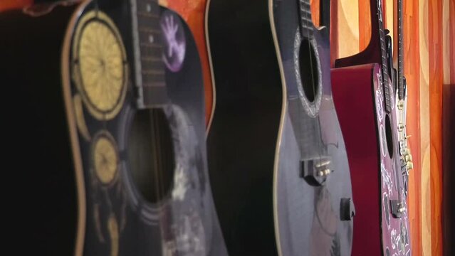 Four multi-colored guitars with drawings and stickers hang on the wall close-up