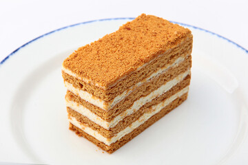 Layered honey cake highlighted on a white background. A piece of honey cake on white plate. Isolated object.