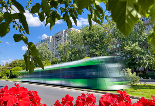 Green tram in motion circulating through a green nature area in Bucharest in the spring season
