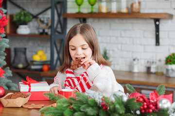 Cute smiling little child girl eating chocolate biscuits and drinking hot cocoa in mug sitting in a...
