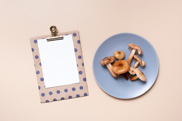 Empty paper with mushrooms in plate on beige background top view, flat lay