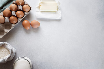 Butter, flour, sugar and carton of eggs on concrete background. Ingredients for baking. Recipe or cookbook concept. Copy space
