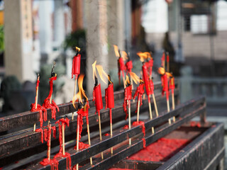 Fototapeta na wymiar Lighting an red incense stick with taper candle in the Chinese temple, pay respect to god