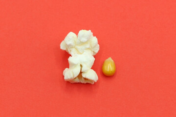 Two popcorn on a red background. One that just exploded and the other quiet.