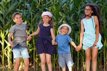 Fototapeta premium Children have fun jumping in front of a cornfield. Happy healthy childhood.