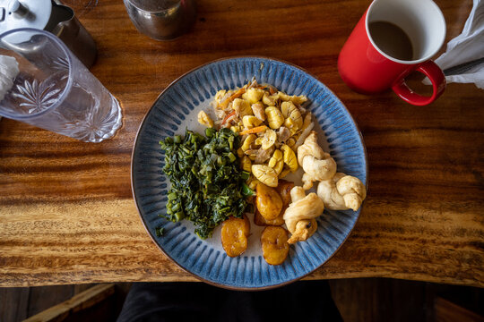 A Jamaican breakfast of ackee & saltfish, sweet plantains, callaloo, fry dumplings, and coffee.
