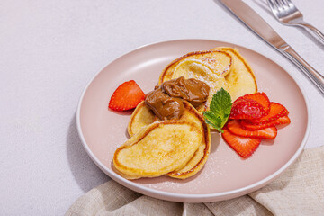 Cottage cheese pancakes, syrniki, curd fritters with strawberry, mint and powdered sugar on plate