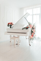 Vertical image white grand piano with beautiful pink roses flowers in white room minimalism...