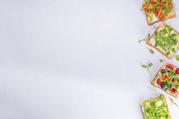 Vegetable and fruit microgreen sandwiches. Homemade toasts sandwiches with tomato, cucumber, berry fruits and a lot of microgreen baby leaves sprouts, white table background copy space