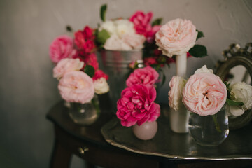 Still life with many different garden roses on a vintage table on grey background.