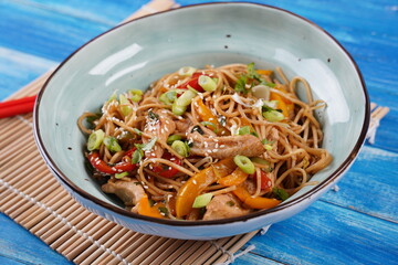 Stir fry noodles with vegetables and chicken meat in a bowl.