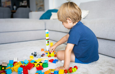 Kid playing with colorful toy blocks. Little boy building tower of block toys. Educational and...